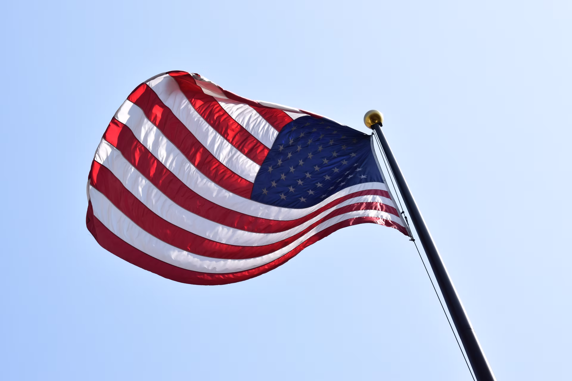 United States flag against a bright blue sky.