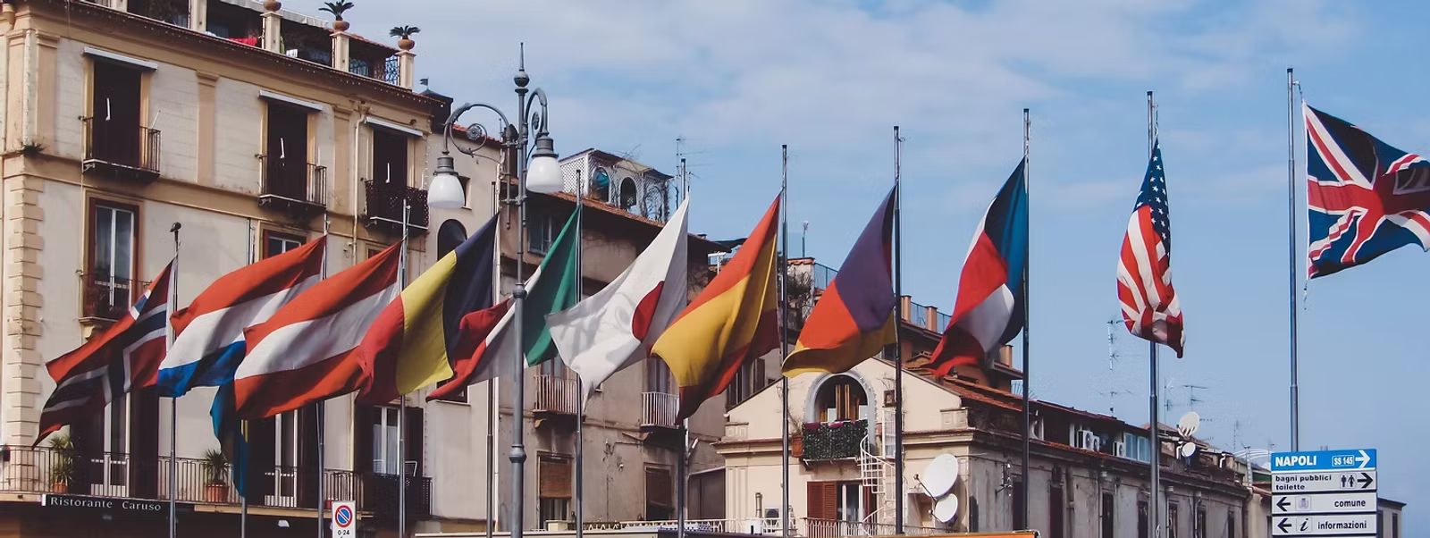 Internationale Flaggen vor klassischer Stadtfassade.